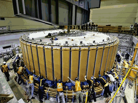 Several dozen workers easing a turbine component into place, in the Revelstoke generating station during installation of unit 5.